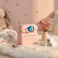 Appareil photo enfant rose avec rouleaux papier thermique fleurs séchées ambiance chambre douce