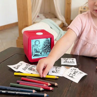 Fillette attrapant ses impressions thermiques collectionnées devant l'imprimante cube rouge