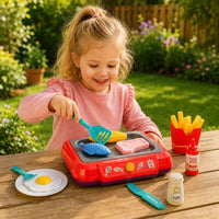 Fillette souriante cuisinant sur plancha jouet rouge avec aliments colorés en extérieur