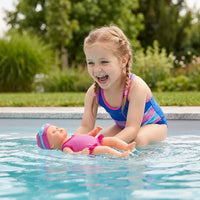 Fillette joyeuse jouant avec poupée nageurs dans piscine extérieure
